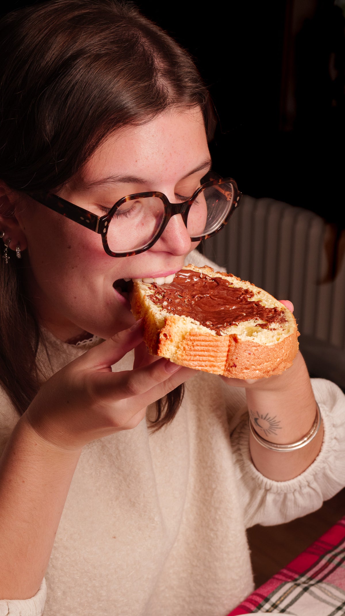 Jeune femme qui croque une tranche de panettone tartinée de L'Écureuil
