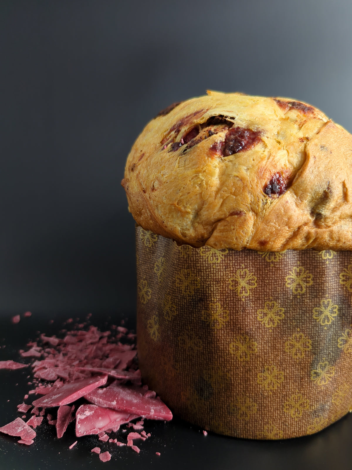 Panettone Le Framboisissimo entier sur fond noir avec éclats de chocolat rubis